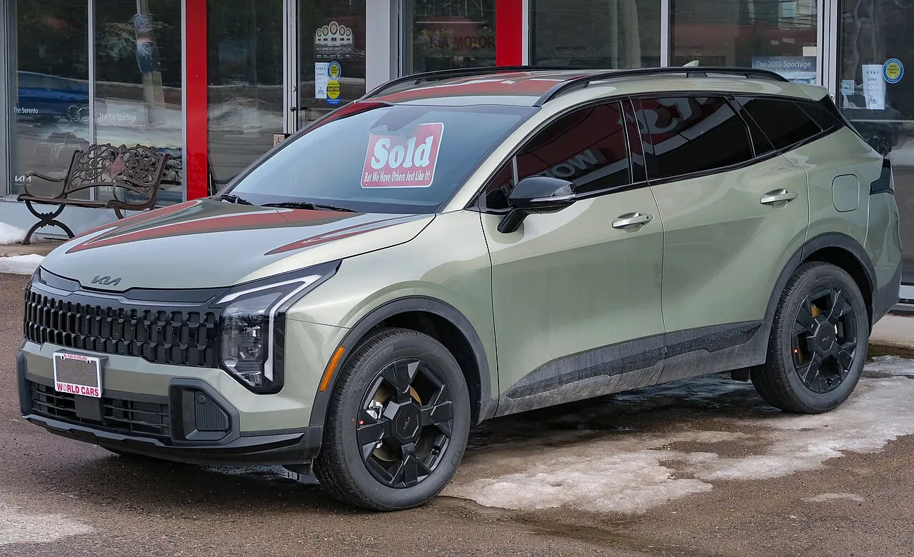 Green Kia Sportage X-Line parked outside a dealership in winter, front three-quarter view