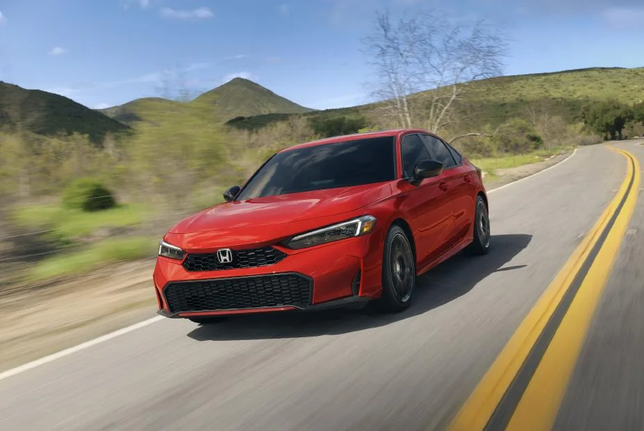 Red 2027 Honda Civic sedan driving on a mountain road, front view