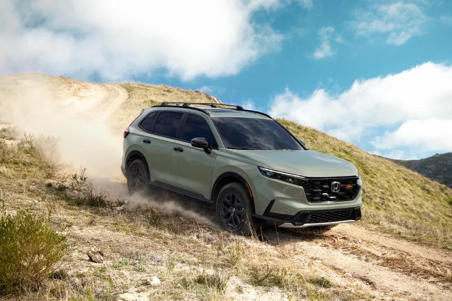 Green Honda CR-V TrailSport Hybrid driving up a dirt hillside