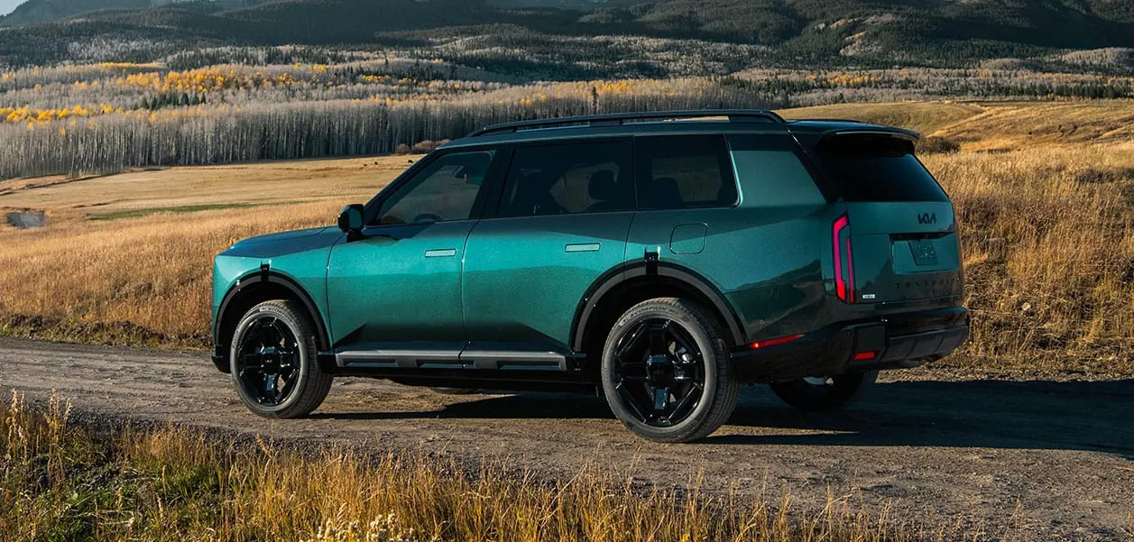 Green 2027 Kia Telluride parked on a gravel road in a meadow